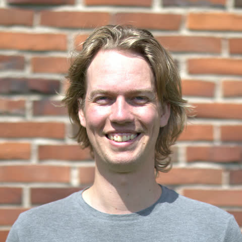 Portræt af Mads Holst Jensen foran en murstensvæg.